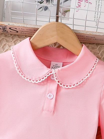 Close-up of the rounded collar, white lace edging and two pink buttons